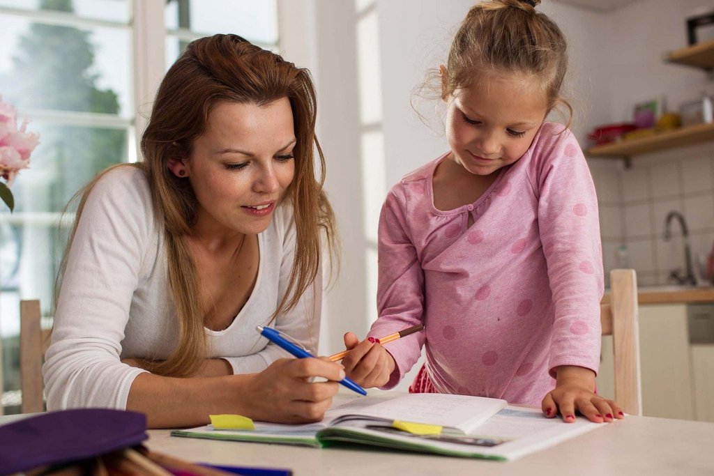 Une maman aide sa fille à faire ses devoirs