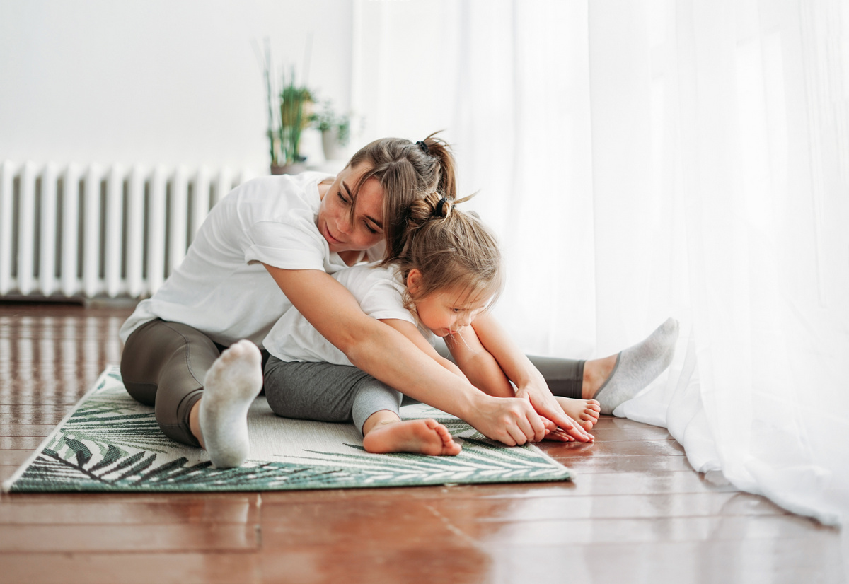 Une maman fait un câlin à sa petite fille en faisant du du yoga