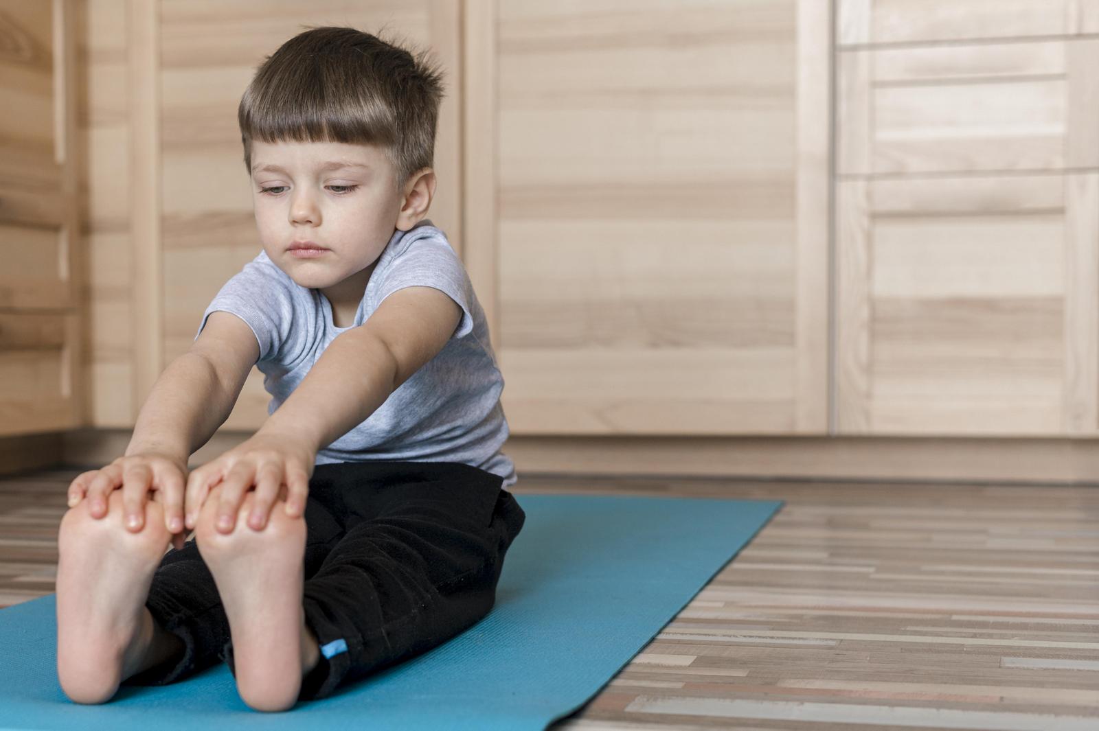 Un petit garçon fait la posture de la pince en yoga