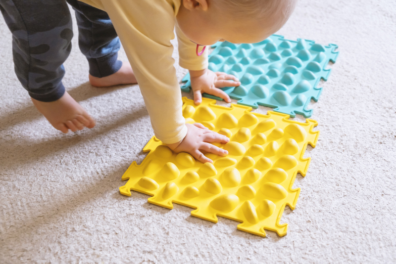 Un bébé joue avec un tapis sensoriel